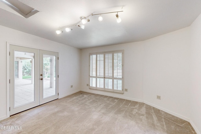 empty room with french doors, light colored carpet, a wealth of natural light, and baseboards