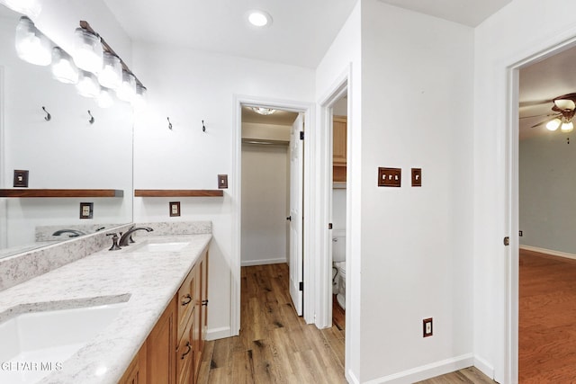 full bathroom featuring ceiling fan, wood finished floors, baseboards, and a sink