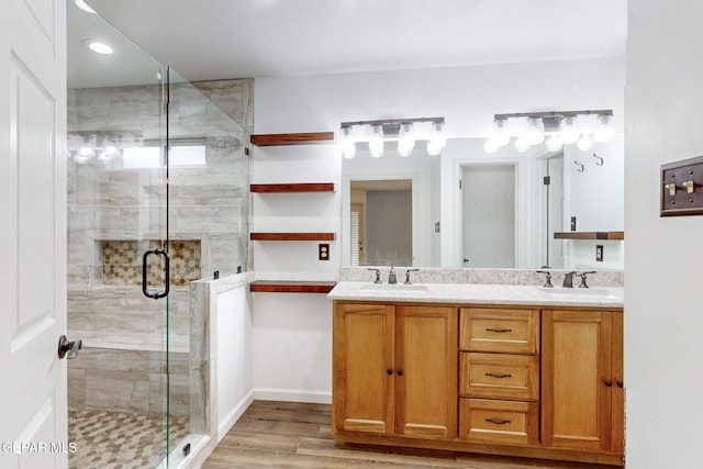 bathroom with double vanity, a stall shower, wood finished floors, and a sink