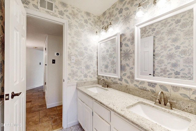 bathroom featuring double vanity, visible vents, wallpapered walls, and a sink