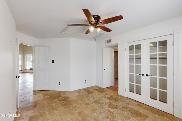 empty room featuring visible vents, a ceiling fan, stone tile flooring, french doors, and baseboards