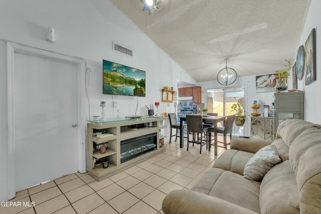 living area featuring visible vents, a notable chandelier, a textured ceiling, light tile patterned floors, and vaulted ceiling