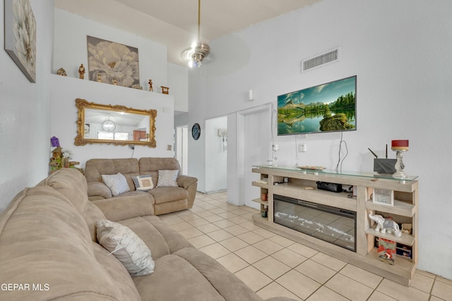 living room with tile patterned flooring, visible vents, and a towering ceiling