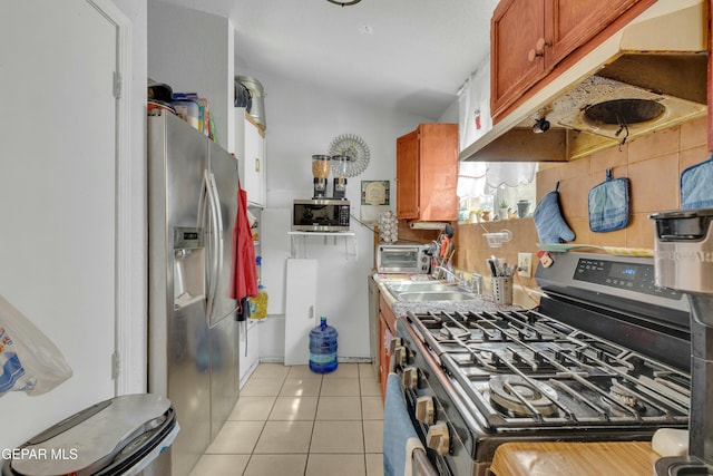 kitchen featuring a sink, under cabinet range hood, tasteful backsplash, stainless steel appliances, and light tile patterned floors