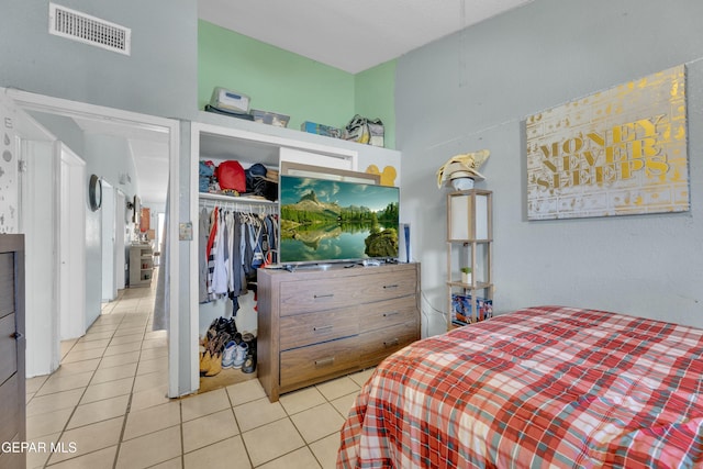 bedroom featuring light tile patterned floors, visible vents, and a closet