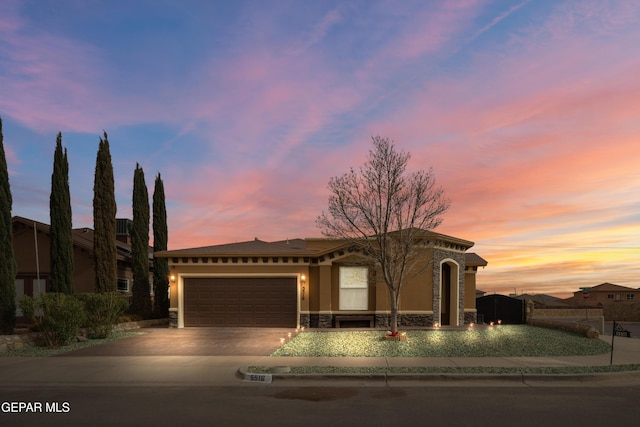 view of front of property featuring a garage, stone siding, driveway, and stucco siding