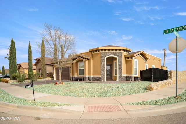 mediterranean / spanish-style house featuring stone siding, stucco siding, an attached garage, and concrete driveway