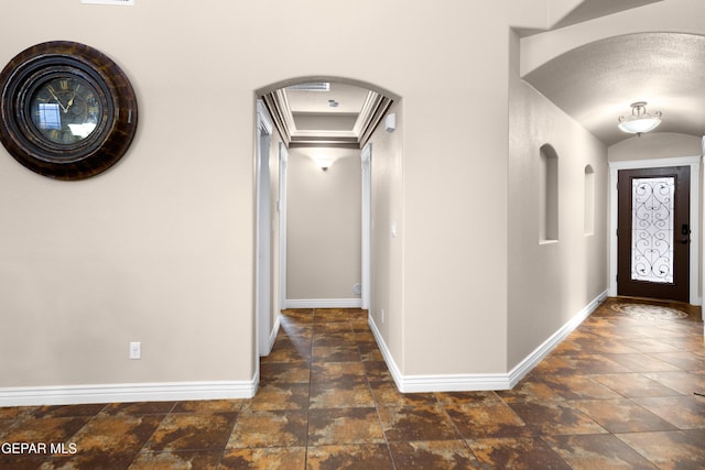 foyer entrance featuring arched walkways, stone finish flooring, and baseboards