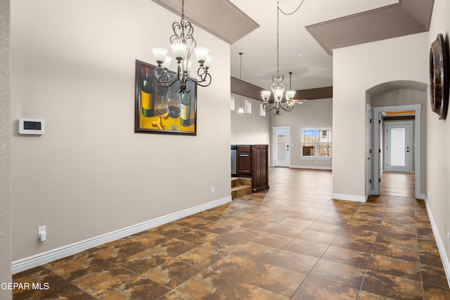 unfurnished dining area with baseboards, arched walkways, and a chandelier