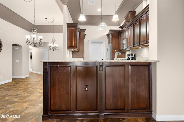 kitchen featuring dark brown cabinetry, pendant lighting, light stone counters, and stainless steel appliances