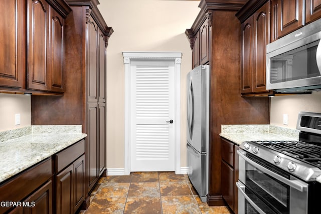 kitchen featuring light stone counters, appliances with stainless steel finishes, and dark brown cabinets