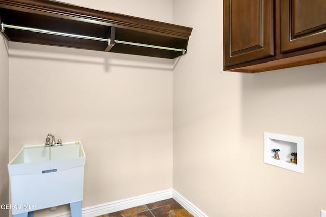 washroom with cabinet space, hookup for a washing machine, baseboards, and a sink