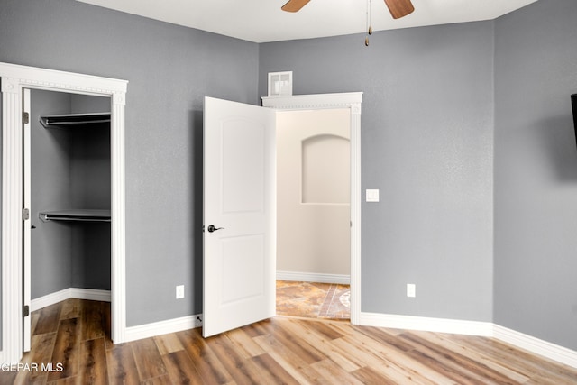 unfurnished bedroom featuring a closet, visible vents, a spacious closet, and wood finished floors