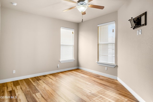 spare room featuring a healthy amount of sunlight, baseboards, light wood-style floors, and ceiling fan