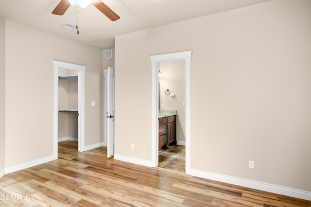 unfurnished bedroom featuring a spacious closet, light wood-style floors, visible vents, and baseboards