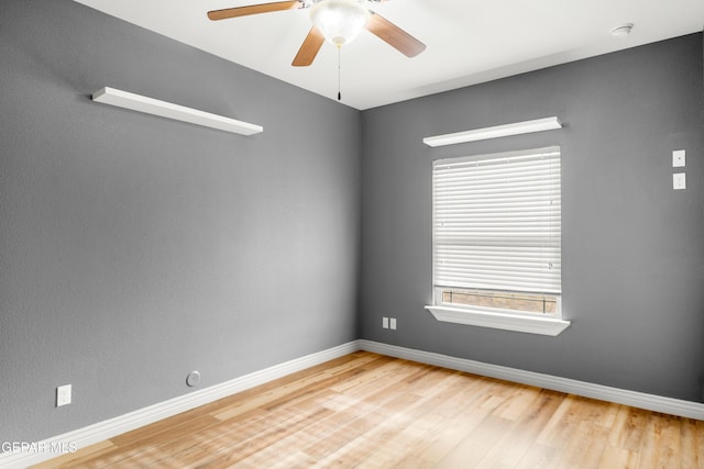 empty room featuring baseboards, wood finished floors, and a ceiling fan