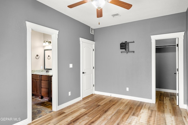 unfurnished bedroom with a spacious closet, baseboards, visible vents, and light wood-type flooring