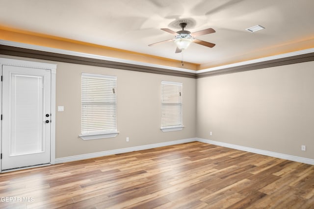 spare room featuring a ceiling fan, visible vents, light wood-style floors, and baseboards