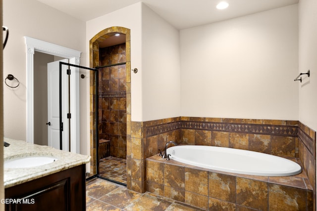 bathroom with a stall shower, vanity, and a garden tub