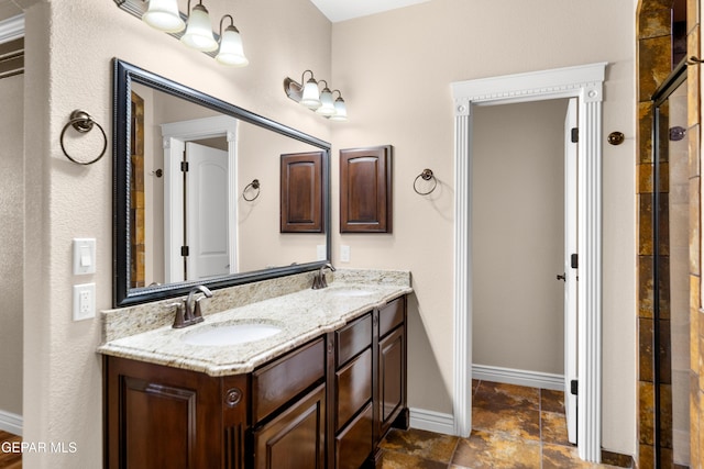 bathroom with a sink, tiled shower, baseboards, and double vanity