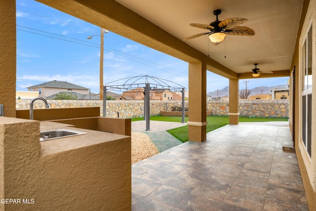 view of patio with a sink, area for grilling, a fenced backyard, and a ceiling fan