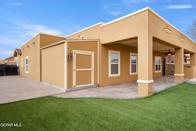 rear view of house featuring a yard, stucco siding, a patio, and ceiling fan