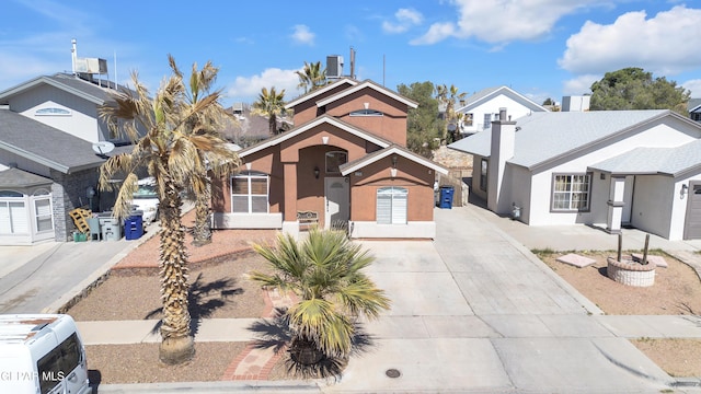 view of front of property with central AC, a residential view, driveway, and stucco siding