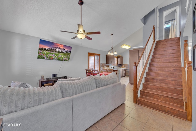 living room with ceiling fan with notable chandelier, a textured ceiling, stairway, light tile patterned floors, and vaulted ceiling