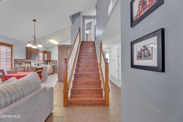 stairs featuring tile patterned flooring, vaulted ceiling, a textured ceiling, and a chandelier