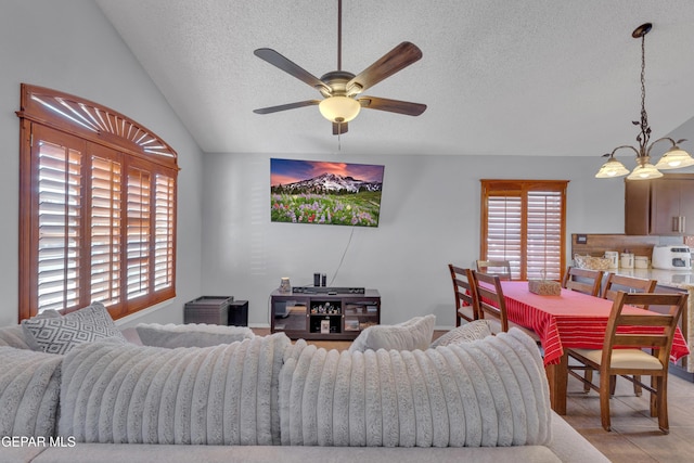 living room with ceiling fan with notable chandelier, a textured ceiling, and lofted ceiling