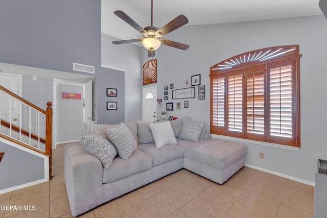 tiled living area with visible vents, baseboards, stairs, high vaulted ceiling, and a ceiling fan