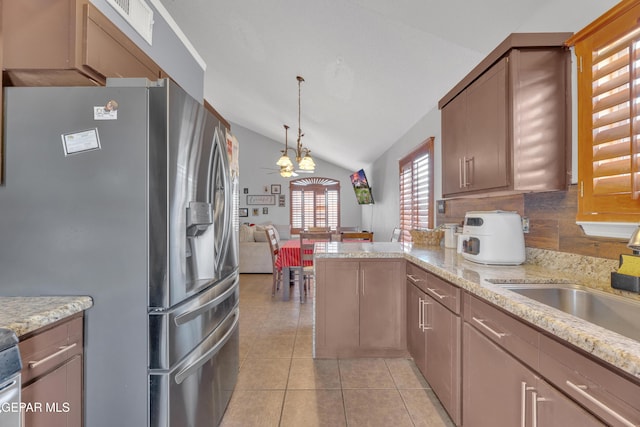 kitchen featuring lofted ceiling, light tile patterned floors, a peninsula, stainless steel refrigerator with ice dispenser, and hanging light fixtures