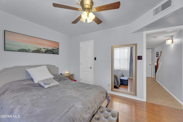 bedroom with visible vents, ceiling fan, baseboards, and wood finished floors