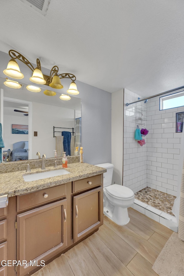 full bath featuring a tile shower, connected bathroom, vanity, and toilet