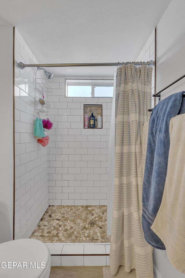 full bath with a shower stall, toilet, and a textured ceiling