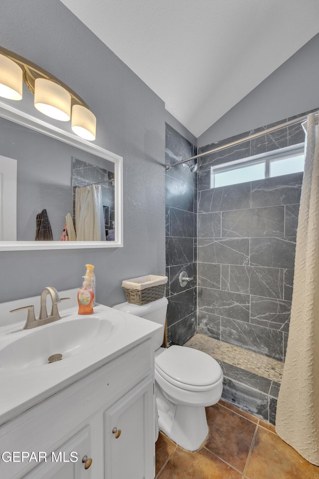 full bathroom featuring vanity, a tile shower, tile patterned flooring, vaulted ceiling, and toilet