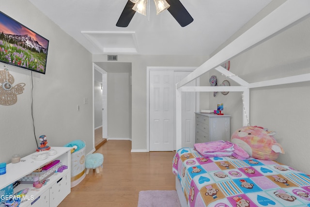 bedroom featuring wood finished floors, baseboards, visible vents, ceiling fan, and a closet