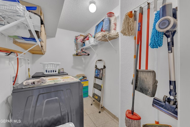 laundry area featuring light tile patterned floors, laundry area, a textured ceiling, and baseboards