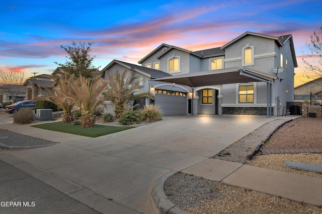 view of front of home featuring stone siding, driveway, central AC, and stucco siding