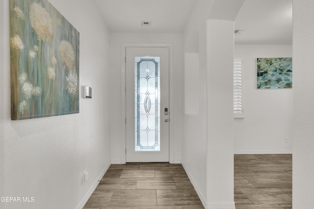 foyer with wood finished floors, baseboards, and visible vents