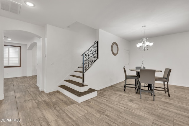 dining room with stairway, visible vents, baseboards, arched walkways, and a notable chandelier