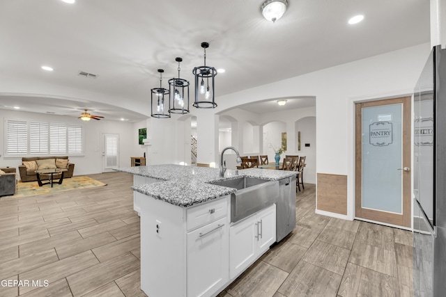 kitchen featuring visible vents, a sink, open floor plan, arched walkways, and dishwasher