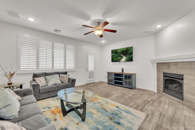 living area with visible vents, recessed lighting, a tile fireplace, wood finished floors, and a ceiling fan