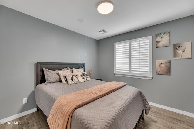 bedroom with visible vents, baseboards, and wood finished floors