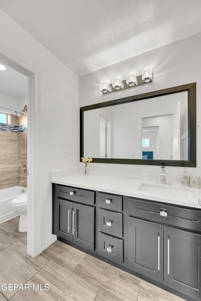 bathroom featuring vanity, shower / tub combination, toilet, and a textured ceiling