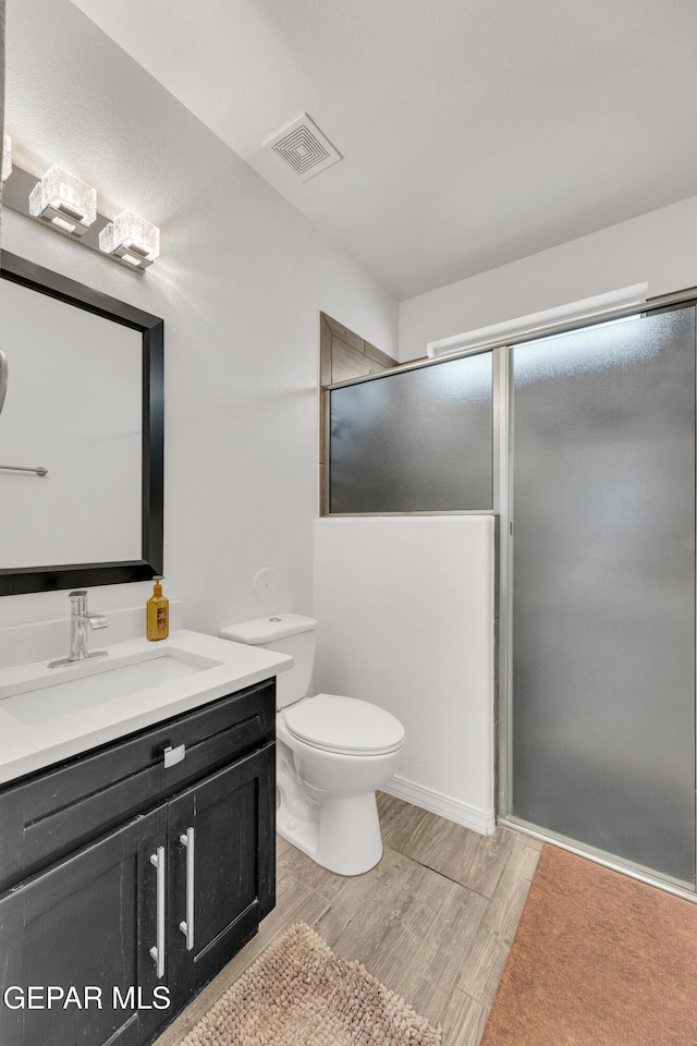 full bathroom featuring visible vents, an enclosed shower, toilet, wood finished floors, and vanity