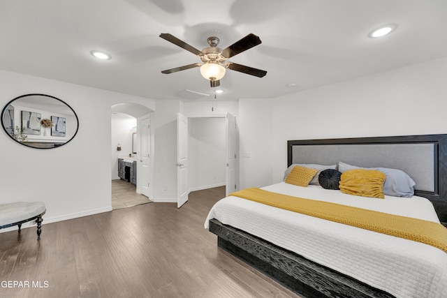 bedroom featuring arched walkways, recessed lighting, baseboards, and wood finished floors