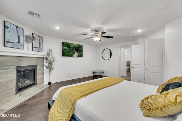 bedroom with visible vents, baseboards, dark wood finished floors, a fireplace, and arched walkways