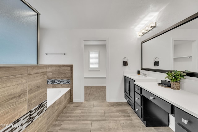 full bathroom featuring a bath, vanity, and baseboards