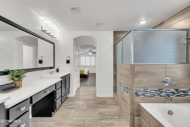 bathroom featuring vanity, visible vents, tiled tub, ceiling fan, and ensuite bathroom